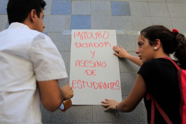 Opposition supporters put up a placard that reads "Maduro dictator and assassin of students" outside a school where a polling center will be established for a Constitutional Assembly election next Sunday, in Caracas, Venezuela July 24, 2017. REUTERS/Marco Bello
