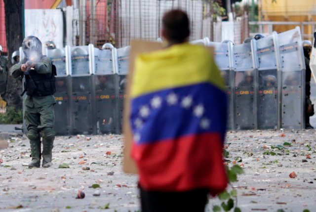  Un hombre con bandera venezolana se alza frente a las fuerzas de seguridad antidisturbios mientras se reúne contra el gobierno del presidente de Venezuela, Nicolás Maduro, en Caracas, Venezuela, el 26 de julio de 2017. REUTERS/Ueslei Marcelino