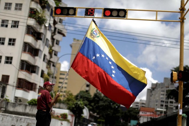 A man with a Venezuelan flag stands in a street after a strike called to protest against Venezuelan President Nicolas Maduro's government in Caracas, Venezuela, July 29, 2017. REUTERS/Ueslei Marcelino