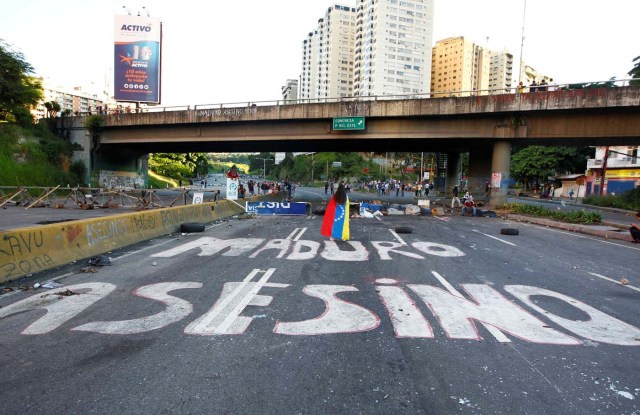 Demonstrators walk on an empty highway with the words "Maduro Assasin" painted on the surface after clashes broke out while the Constituent Assembly election was being carried out in Caracas, Venezuela, July 30, 2017. REUTERS/Christian Veron TPX IMAGES OF THE DAY