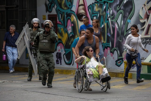 CAR137. CARACAS (VENEZUELA), 20/07/2017.- Agentes de la Guardia Nacional Bolivariana ayudan a transeúntes a evitar la zona donde se enfrentan con manifestantes opositores hoy, jueves 20 de julio de 2017, en Caracas (Venezuela). Sectores enteros de Caracas permanecen hoy cerrados al tráfico en seguimiento del paro general de 24 horas convocado por la oposición contra el presidente, Nicolás Maduro, en una nueva acción de protesta antigubernamental que atrancó las comunicaciones y provocó el cierre de buena parte de los negocios. EFE/Cristian Hernández