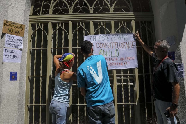 CAR09. CARACAS (VENEZUELA), 24/07/2017.- Manifestantes pegan carteles en rechazo a la Asamblea Constituyente hoy, lunes 24 de julio de 2017, en un colegio electoral de Caracas (Venezuela). Venezuela inicia hoy la semana decisiva para la elección de la Asamblea Nacional Constituyente convocada por el presidente, Nicolás Maduro, con los oficialistas entrando en la recta final de su campaña en medio de protestas y llamados a paro de los opositores en rechazo a esos comicios. EFE/Miguel Gutiérrez