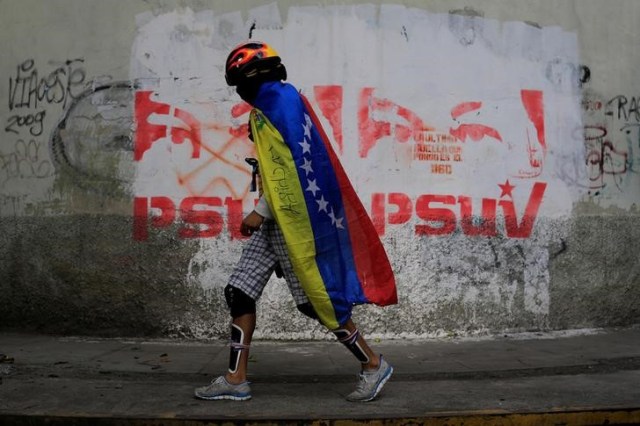 Un manifestante cubierto con una bandera de Venezuela camina por una calle en una jornada de huelga en Caracas, jul 26, 2017.  REUTERS/Marco Bello