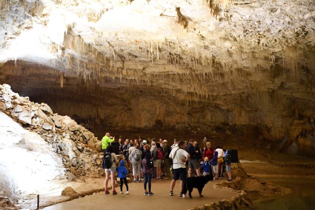 People listen to a guide (L) as they visit the natural cave of Choranche, in the Vercors region near Grenoble, on August 3, 2017. Since the beginning of the heat wave, there has been an increase of at least 10 percent in the number of cave visitors, looking for beautiful natural sites, but also for underground freshness with temperatures around 15 Degrees Celsius. / AFP PHOTO / JEAN-PIERRE CLATOT