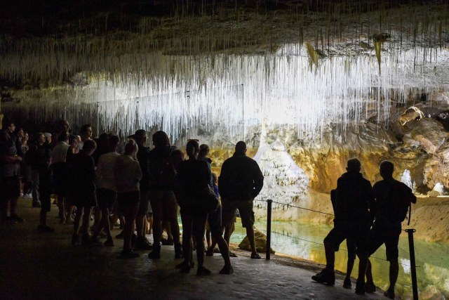 People visit the natural cave of Choranche, in the Vercors region near Grenoble, on August 3, 2017. Since the beginning of the heat wave, there has been an increase of at least 10 percent in the number of cave visitors, looking for beautiful natural sites, but also for underground freshness with temperatures around 15 Degrees Celsius. / AFP PHOTO / JEAN-PIERRE CLATOT