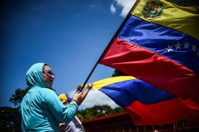 An anti-government activist demonstrates against Venezuelan President Nicolas Maduro at a barricade set up on a road in Caracas on August 8, 2017. Recent demonstrations in Venezuela have stemmed from anger over the installation of an all-powerful Constituent Assembly that many see as a power grab by the unpopular President Maduro. The dire economic situation also has stirred deep bitterness as people struggle with skyrocketing inflation and shortages of food and medicine. / AFP PHOTO / Ronaldo SCHEMIDT