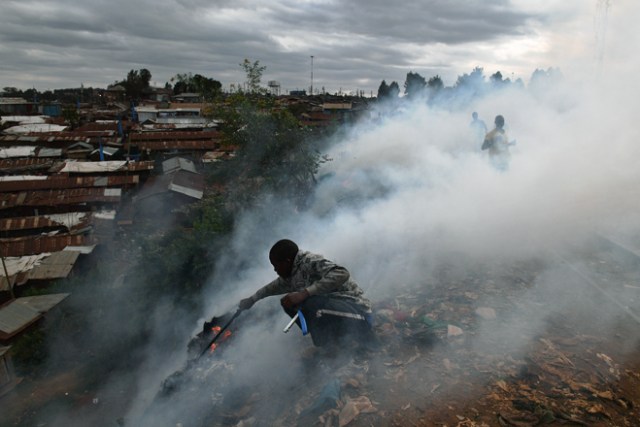 A boy with a stick tries to save belongings from a fire in the Kibera slum in Nairobi on August 12, 2017 Three people, including a child, have been shot dead in Kenya during opposition protests which flared for a second day Saturday after the hotly disputed election victory of President Uhuru Kenyatta. Demonstrations and running battles with police broke out in isolated parts of Nairobi slums after anger in opposition strongholds against August 8 election that losing candidate Raila Odinga claims was massively rigged. / AFP PHOTO / CARL DE SOUZA
