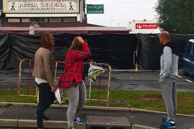 Members of the public react in front of the scene of a car crash into a pizza restaurant on August 15, 2017 in Sept-Sorts, 55km east of Paris, which resulted in the death of a 13-year-old girl and 13 seriously injured. Investigators said the young driver had tried to commit suicide and the incident was not terror-related. The man, who was arrested, said "he had tried to kill himself yesterday (August 13) without success and decided to try again this way," a source close to the inquiry said. / AFP PHOTO / Sarah BRETHES