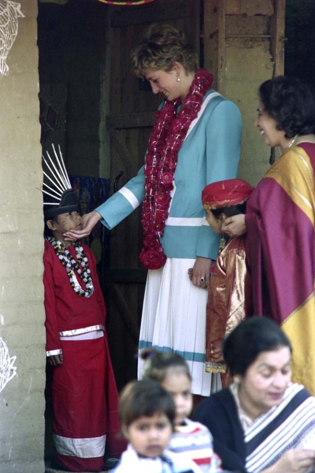 (FILES) This file photo taken on February 12, 1992 shows Britain's Diana, Princess of Wales, holding the face of an Indian boy during her visit to Tamana Arts and Crafts School in New Dehli. Princess Diana revolutionised the royal dress code with the help of some of the world's greatest designers during a glamorous life that came to a tragic end on August 31, 1997, 20 years ago this month. / AFP PHOTO / RAVEENDRAN