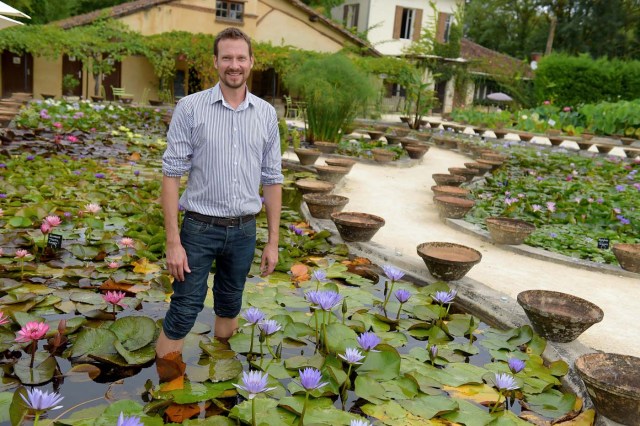 US-French Robert Sheldon poses among water lilies at the Latour-Marliac nursery in Le Temple-sur-Lot, southwestern France, on August 23, 2017. The Latour-Marliac nursery, a first of its kind in Europe, has been growing coloured water lilies since 1870 and was a source of inspiration for French painter Claude Monet's "Water Lilies" (Nympheas) series. / AFP PHOTO / Nicolas TUCAT
