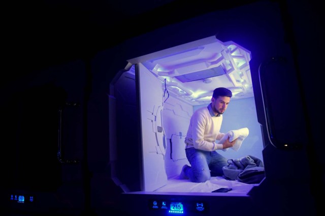 Argentinian Ignacio Ponce arranges his belongings inside a sleeping capsule at the Benito Juarez International Airport in Mexico City on August 25, 2017. / AFP PHOTO / PEDRO PARDO