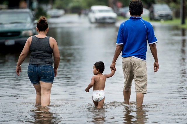 People walk through flooded streets as the effects of Hurricane Henry are seen August 26, 2017 in Galveston, Texas. Hurricane Harvey left a trail of devastation Saturday after the most powerful storm to hit the US mainland in over a decade slammed into Texas, destroying homes, severing power supplies and forcing tens of thousands of residents to flee. / AFP PHOTO / Brendan Smialowski
