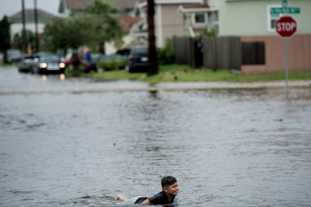 A boy plays in a flooded street as the effects of Hurricane Henry are seen August 26, 2017 in Galveston, Texas. Hurricane Harvey left a trail of devastation Saturday after the most powerful storm to hit the US mainland in over a decade slammed into Texas, destroying homes, severing power supplies and forcing tens of thousands of residents to flee. / AFP PHOTO / Brendan Smialowski