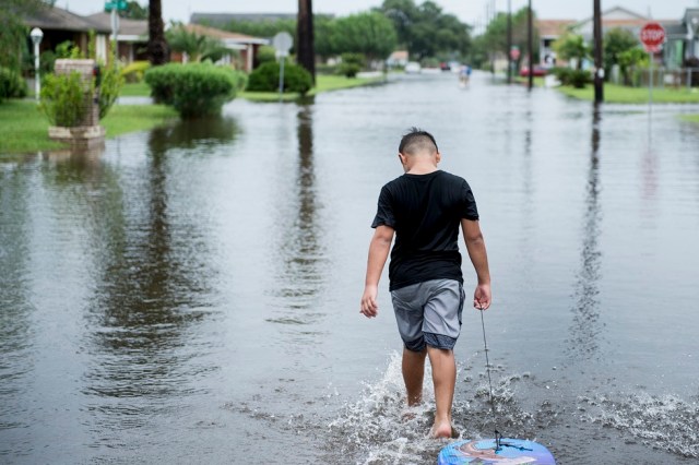 A boy walks with a bodyboard through a flooded street as the effects of Hurricane Henry are seen August 26, 2017 in Galveston, Texas. Hurricane Harvey left a trail of devastation Saturday after the most powerful storm to hit the US mainland in over a decade slammed into Texas, destroying homes, severing power supplies and forcing tens of thousands of residents to flee. / AFP PHOTO / Brendan Smialowski