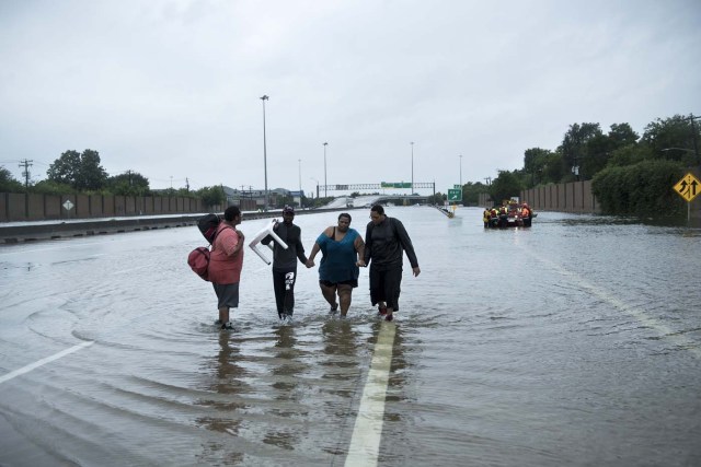 People make their way onto an I-610 overpass after being rescued from flooded homes during the aftermath of Hurricane Harvey August 27, 2017 in Houston, Texas. Hurricane Harvey left a trail of devastation after the most powerful storm to hit the US mainland in over a decade slammed into Texas, destroying homes, severing power supplies and forcing tens of thousands of residents to flee. / AFP PHOTO / Brendan Smialowski