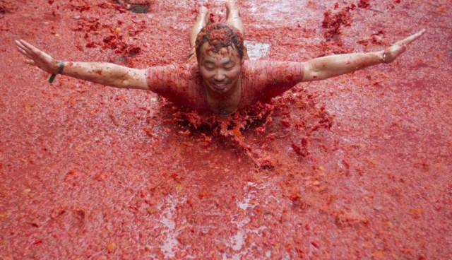 A reveller covered in tomato pulp takes part in the annual "Tomatina" festival in the eastern town of Bunol, on August 30, 2017. The iconic fiesta -- which celebrates its 72nd anniversary and is billed at "the world's biggest food fight" -- has become a major draw for foreigners, in particular from Britain, Japan and the United States. / AFP PHOTO / JAIME REINA