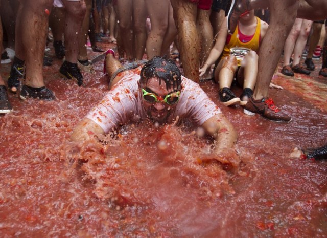 A reveller covered in tomato pulp takes part in the annual "Tomatina" festival in the eastern town of Bunol, on August 30, 2017. The iconic fiesta -- which celebrates its 72nd anniversary and is billed at "the world's biggest food fight" -- has become a major draw for foreigners, in particular from Britain, Japan and the United States. / AFP PHOTO / JAIME REINA