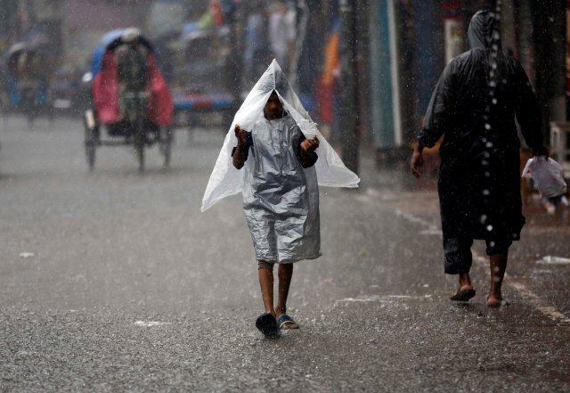 A boy covers his body with polythene sheet while walking on the road during heavy rain in Dhaka, Bangladesh July 26, 2017. REUTERS/Mohammad Ponir Hossain