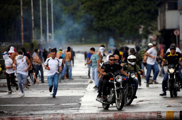 Demonstrators run and ride their motorcycles near Fuerte Paramacay military base during clashes with security forces in Valencia, Venezuela August 6, 2017. REUTERS/Andres Martinez Casares