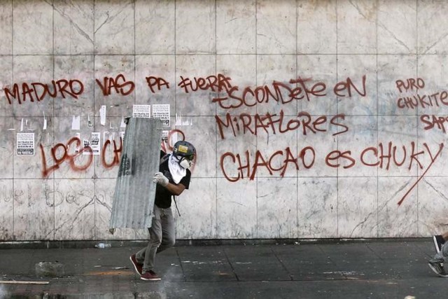 Un manifestante opositor al Gobierno de Venezuela corre en un intento por cubrirse de agentes de la guardia nacional durante una protesta en el distrito de Chacao, en Caracas. Foto de archivo. REUTERS/Christian Verón