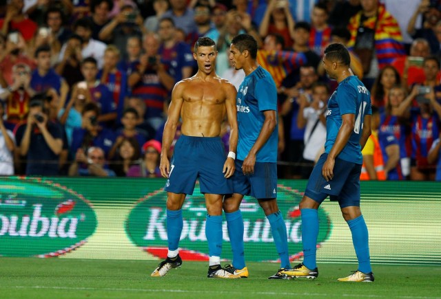 Soccer Football - Barcelona v Real Madrid Spanish Super Cup First Leg - Barcelona, Spain - August 13, 2017   Real Madrid’s Cristiano Ronaldo celebrates scoring their second goal with Raphael Varane and Casemiro and is later booked for removing his shirt   REUTERS/Juan Medina