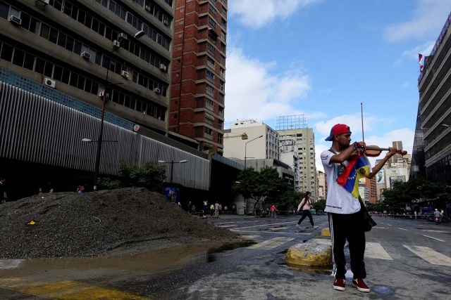 FILE PHOTO - Venezuelan violinist Wuilly Arteaga plays the violin next to a pile of sand used by protesters to block the street during a protest against Venezuelan President Nicolas Maduro's government in Caracas, Venezuela July 18, 2017. REUTERS/Carlos Garcia Rawlins/File Photo