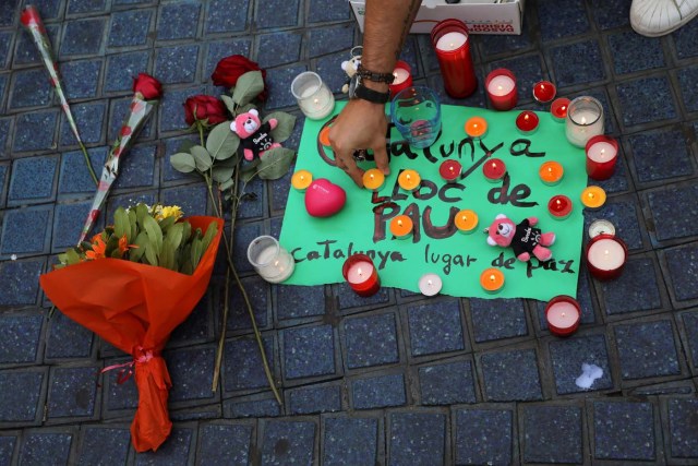 A person places a candle on a placard, reading in Spanish and Catalan "Catalonia, place of peace", in the area where a van crashed into pedestrians at Las Ramblas street in Barcelona, Spain August 18, 2017. REUTERS/Sergio Perez