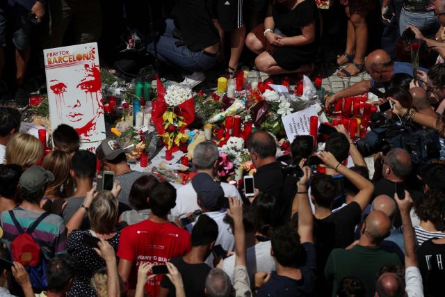 People gather around flowers and candles at Las Ramblas the day after a van crashed into pedestrians in Barcelona, Spain, August 18, 2017. REUTERS/Sergio Perez