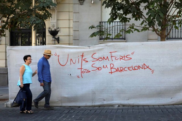 A couple walks past a graffiti that reads "United we are strong, we are all Barcelona" in Madrid, Spain, August 18, 2017. REUTERS/Juan Medina
