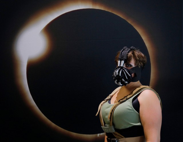 Cassie Gillard, from bay City Michigan and dressed as Lady Bane from the Batman franchise, poses for a photograph in front of an image of a solar eclipse at the Eclipse Comic-Con at Southern Illinois University in Carbondale, Illinois, U.S., August 20, 2017 one day before a total solar eclipse in the city.   REUTERS/Brian Snyder