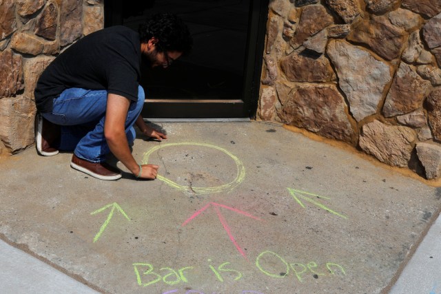 A man chalks an advertisement for the Varsity Gallery bar in Carbondale, Illinois, U.S., August 20, 2017, one day before the total solar eclipse. REUTERS/Brian Snyder