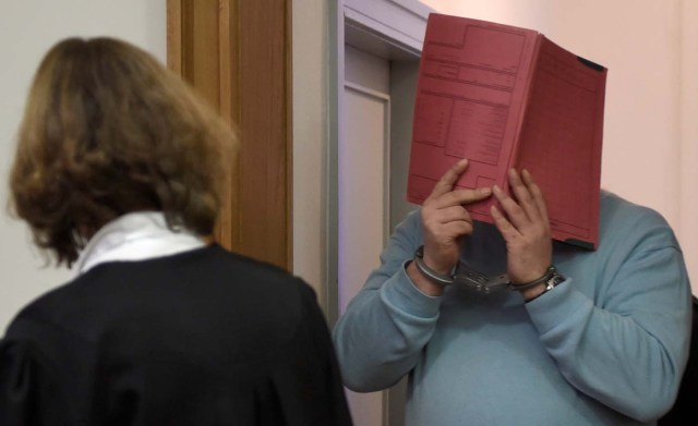 FILE PHOTO: Former nurse Niels H. (R) masks his face with a folder on his arrival in the courtroom at the regional court in Oldenburg, December 9, 2014.     REUTERS/Fabian Bimmer/File Photo