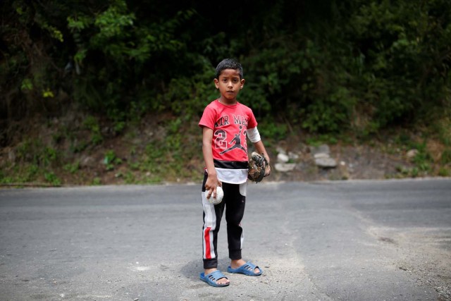 Luis Mejia, 7, poses for a picture after practice baseball on the street in Caracas, Venezuela August 29, 2017. Picture taken August 29, 2017. REUTERS/Carlos Garcia Rawlins