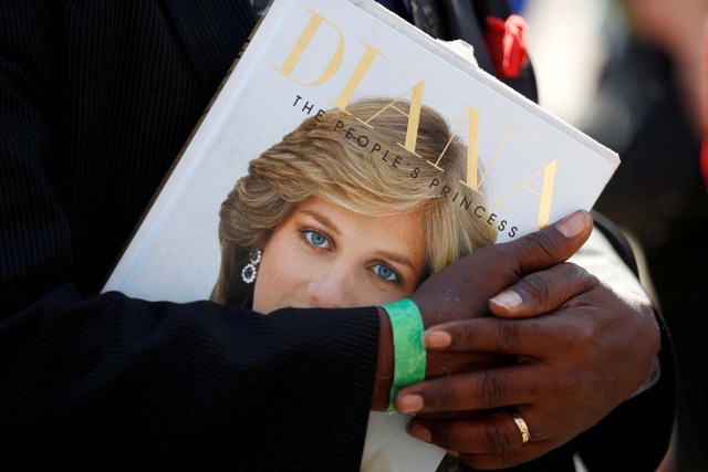 REFILE - CORRECTING BYLINE A royal fan cradles a book about the late Princess Diana at the gates of her former residence in Kensington Palace on the twentieth anniversary of her death, in London, Britain August 31, 2017. REUTERS/Peter Nicholls