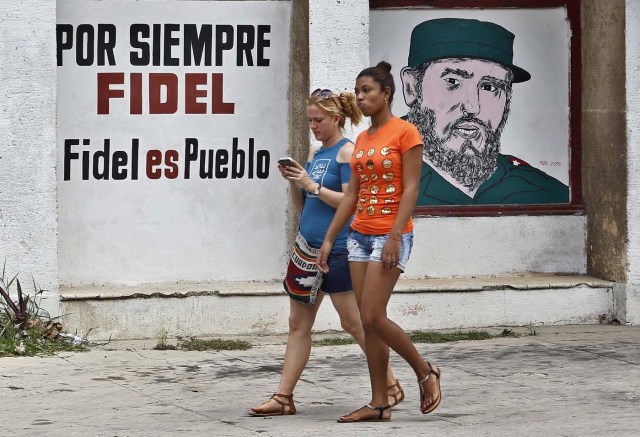 HAB101. LA HABANA (CUBA), 13/08/2017.- Dos jóvenes pasan frente a un grafiti con la imagen del líder de la revolución cubana, Fidel Castro, en el día de su 91 cumpleaños, hoy, domingo 13 de agosto del 2017, en La Habana (Cuba). Cuba recuerda hoy el 91 aniversario del natalicio del líder de la revolución, Fidel Castro, el primero tras su fallecimiento hace nueve meses, que se celebra este domingo con múltiples actos y una amplia cobertura en los medios estatales de la isla que resaltan el legado del "invicto y eterno Comandante". EFE/Ernesto Mastrascusa