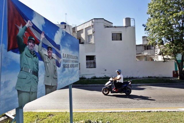 HAB105. LA HABANA (CUBA), 13/08/2017.- Un hombre en moto pasa junto a un cartel con la imagen del líder de la revolución cubana Fidel Castro, en el día de su 91 cumpleaños, hoy, domingo 13 de agosto del 2017, en La Habana (Cuba). Cuba recuerda hoy el 91 aniversario del natalicio del líder de la revolución, Fidel Castro, el primero tras su fallecimiento hace nueve meses, que se celebra este domingo con múltiples actos y una amplia cobertura en los medios estatales de la isla que resaltan el legado del "invicto y eterno Comandante". EFE/Ernesto Mastrascusa