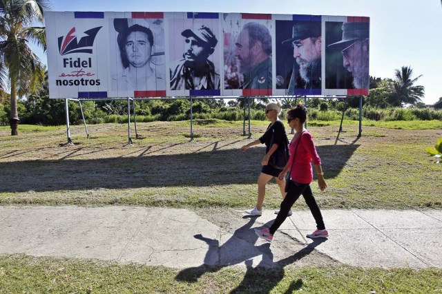HAB106. LA HABANA (CUBA), 13/08/2017.- Dos mujeres caminan junto a un cartel con la imagen del líder de la revolución cubana Fidel Castro, en el día de su 91 cumpleaños, hoy, domingo 13 de agosto del 2017, en La Habana (Cuba). Cuba recuerda hoy el 91 aniversario del natalicio del líder de la revolución, Fidel Castro, el primero tras su fallecimiento hace nueve meses, que se celebra este domingo con múltiples actos y una amplia cobertura en los medios estatales de la isla que resaltan el legado del "invicto y eterno Comandante". EFE/Ernesto Mastrascusa