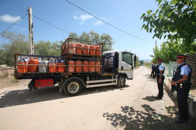 Un camión (i) retira parte de las 120 bombonas de butano halladas en el chalet de Alcanar Platja utilizado por los terroristas de Barcelona y Cambrils 