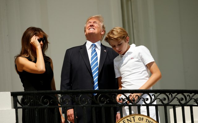 Without his protective glasses on, U.S. President Donald Trump looks up towards the solar eclipse while viewing with his wife Melania and son Barron at the White House in Washington, U.S., August 21, 2017.  REUTERS/Kevin Lamarque