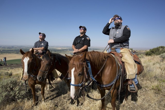 MENAN, ID - AUGUST 21: The Madison County Sheriff's Mounted Patrol watch the eclipse atop horses on Menan Butte to watch the eclipse on August 21, 2017 in Menan, Idaho. Millions of people have flocked to areas of the U.S. that are in the "path of totality" in order to experience a total solar eclipse. Natalie Behring/Getty Images/AFP