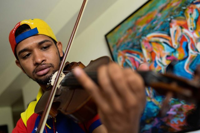 Opposition activist and violinist Wuilly Arteaga, plays his instrument during an interview with AFP in Caracas on September 1, 2017. Arteaga, 23, said that it is dificcult to beleave that "all is so quiet", that the streets "faded away". / AFP PHOTO / FEDERICO PARRA