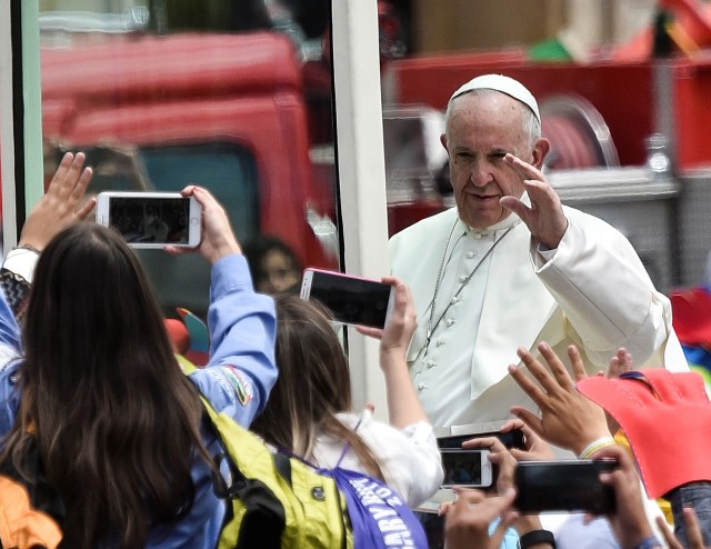 Pope Francis waves from the popemobile at people gathering at Bolivar Square in Bogota on September 7, 2017. Pope Francis urged Colombians to avoid seeking "vengeance" for the sufferings of their country's half-century civil conflict as they work towards a lasting peace. The 80-year-old pontiff spoke alongside Colombia's President Juan Manuel Santos, who has overseen recent controversial efforts to make peace with armed rebel groups. / AFP PHOTO / Luis ROBAYO
