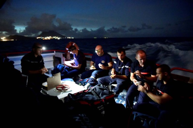 Rescue teams of French fire fighters and civilian security members, ride on a ship to the French Saint-Martin island, devastated by hurricane Irma, after leaving Pointe-a-Pitre harbor on September 8, 2017. Officials on the island of Guadeloupe, where French aid efforts are being coordinated, suspended boat crossings to the hardest-hit territories of St Martin and St Barts where 11 people have died. Two days after Hurricane Irma swept over the eastern Caribbean, killing at least 17 people and devastating thousands of homes, some islands braced for a second battering from Hurricane Jose this weekend. / AFP PHOTO / Martin BUREAU