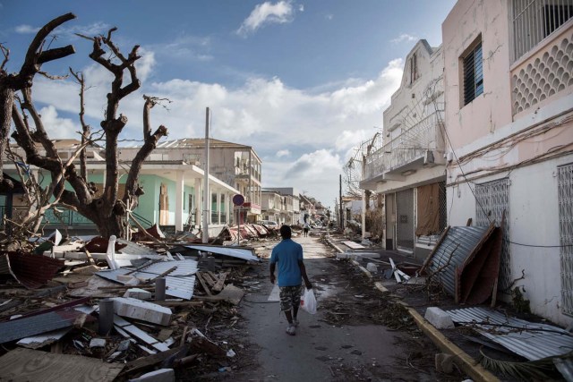 A man walks on a street covered in debris after hurricane Irma hurricane passed on the French island of Saint-Martin, near Marigot on September 8, 2017. Officials on the island of Guadeloupe, where French aid efforts are being coordinated, suspended boat crossings to the hardest-hit territories of St Martin and St Barts where 11 people have died. Two days after Hurricane Irma swept over the eastern Caribbean, killing at least 17 people and devastating thousands of homes, some islands braced for a second battering from Hurricane Jose this weekend. / AFP PHOTO / Martin BUREAU