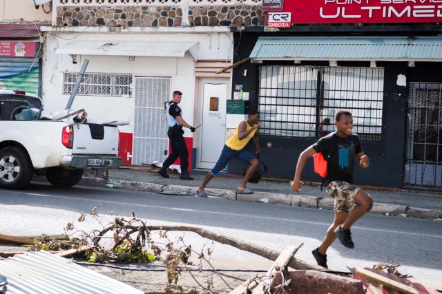A soldier of the French Gendarmerie chases looters as the run past the devastation from hurricane Irma, on the French island of Saint-Martin, near Marigot on September 8, 2017. Officials on the island of Guadeloupe, where French aid efforts are being coordinated, suspended boat crossings to the hardest-hit territories of St Martin and St Barts where 11 people have died. Two days after Hurricane Irma swept over the eastern Caribbean, killing at least 17 people and devastating thousands of homes, some islands braced for a second battering from Hurricane Jose this weekend. / AFP PHOTO / Martin BUREAU