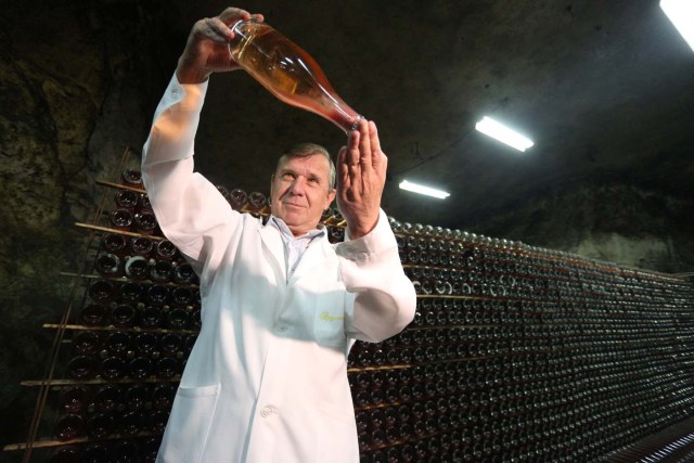 Winemaker Rafail Nasyrov holds a bottle of wine in the "Artwinery" winery firm in the eastern Ukrainian city of Bakhmut on July 12, 2017. The winery is located in a government-held town just two dozen kilometres (15 miles) from the frontline in Ukraine's low-level war, where the army and Russian-backed rebels continue to lob deadly artillery barrages at each other. The town spent around a month under rebel control in 2014, and in 2015 the frontline was so close that the town came under rebel shelling. But despite more than three years of fighting that has claimed some 10,000 lives, Nasyrov's employer, Artwinery, has never stopped production. / AFP PHOTO / Aleksey FILIPPOV