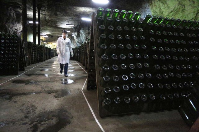 An employee walks past bottles in the "Artwinery" winery firm in the eastern Ukrainian city of Bakhmut on July 12, 2017. The winery is located in a government-held town just two dozen kilometres (15 miles) from the frontline in Ukraine's low-level war, where the army and Russian-backed rebels continue to lob deadly artillery barrages at each other. The town spent around a month under rebel control in 2014, and in 2015 the frontline was so close that the town came under rebel shelling. But despite more than three years of fighting that has claimed some 10,000 lives, Nasyrov's employer, Artwinery, has never stopped production. / AFP PHOTO / Aleksey FILIPPOV
