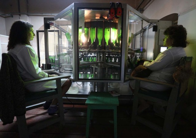 Employees work on the production line in the "Artwinery" winery firm in the eastern Ukrainian city of Bakhmut on July 12, 2017. The winery is located in a government-held town just two dozen kilometres (15 miles) from the frontline in Ukraine's low-level war, where the army and Russian-backed rebels continue to lob deadly artillery barrages at each other. The town spent around a month under rebel control in 2014, and in 2015 the frontline was so close that the town came under rebel shelling. But despite more than three years of fighting that has claimed some 10,000 lives, Nasyrov's employer, Artwinery, has never stopped production. / AFP PHOTO / Aleksey FILIPPOV