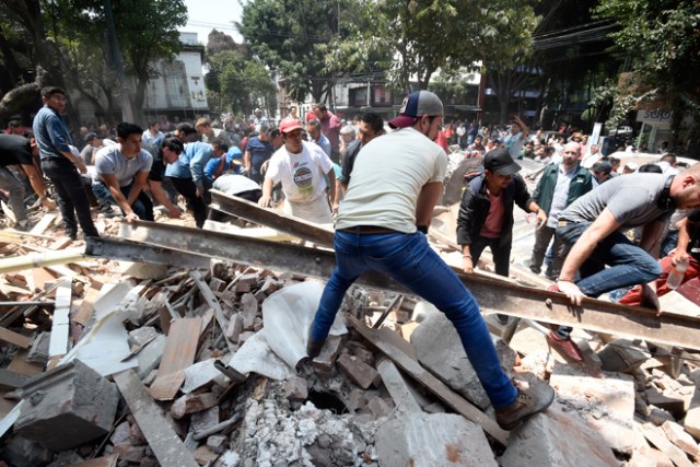 People remove debris of a building which collapsed after a quake rattled Mexico City on September 19, 2017. A powerful earthquake shook Mexico City on Tuesday, causing panic among the megalopolis' 20 million inhabitants on the 32nd anniversary of a devastating 1985 quake. The US Geological Survey put the quake's magnitude at 7.1 while Mexico's Seismological Institute said it measured 6.8 on its scale. The institute said the quake's epicenter was seven kilometers west of Chiautla de Tapia, in the neighboring state of Puebla.  / AFP PHOTO / Alfredo ESTRELLA