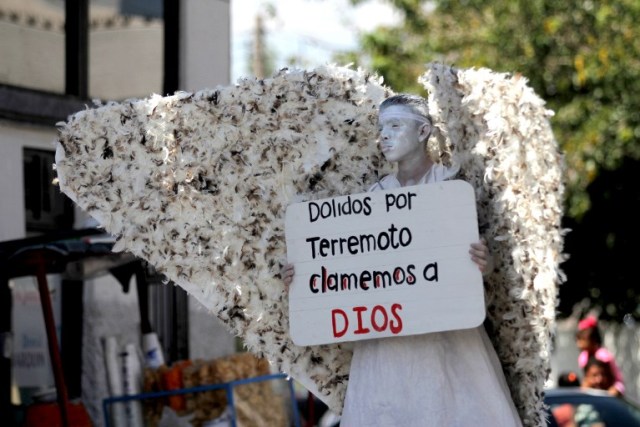 A member of Christian church Salmo 100 dressed as an angel shows a message addressed to the victims of the last earthquake in Mexico City, in front of drivers crossing the Cordova-Americas International Bridge between Ciudad Juarez, Chihuahua state and El Paso, Texas on September 23, 2017 in Ciudad Juárez, Chihuahua, Mexico. / AFP PHOTO / HÉRIKA MARTÍNEZ